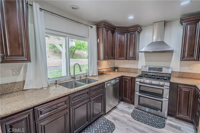 a kitchen with granite countertop a sink a counter space appliances and cabinets