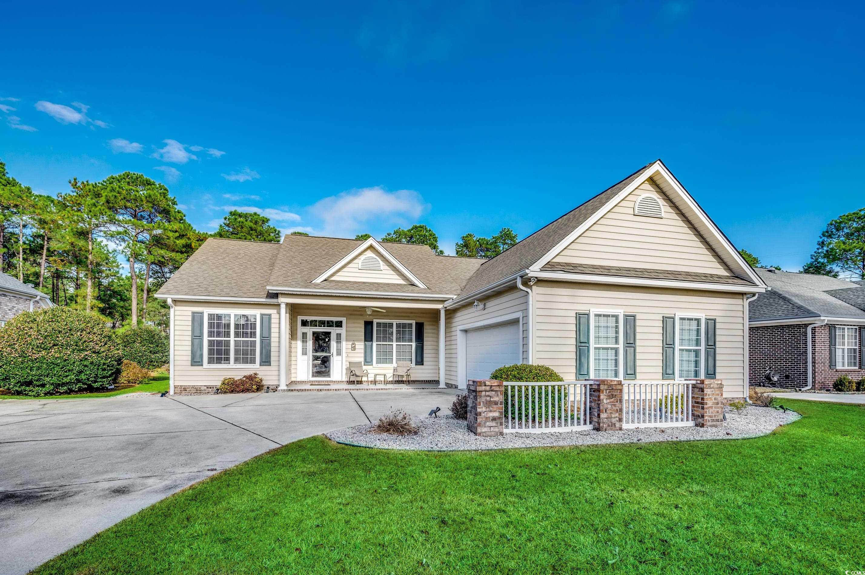 View of front of property with a front yard, concrete driveway, covered porch, a garage, and roof with shingles