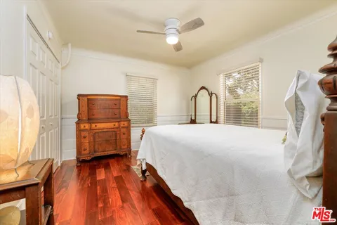 a bedroom with a bed dresser and a large window