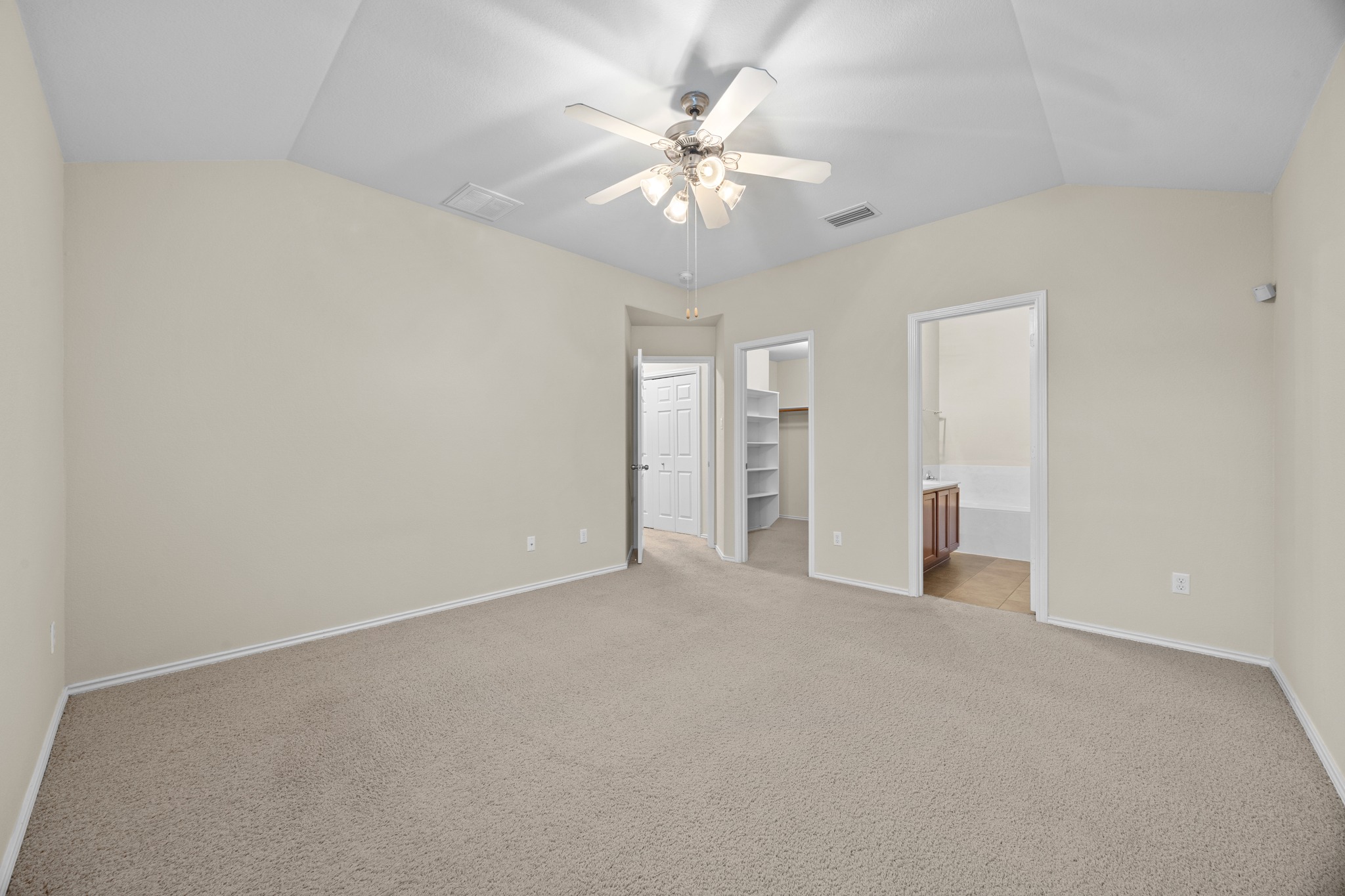 418 Nottingham Loop Kyle, TX 78640 - Photo 18 of 28 Spacious carpeted room featuring a vaulted ceiling with a ceiling fan, light-toned wall paint, white baseboards, and two open doorways revealing interior spaces