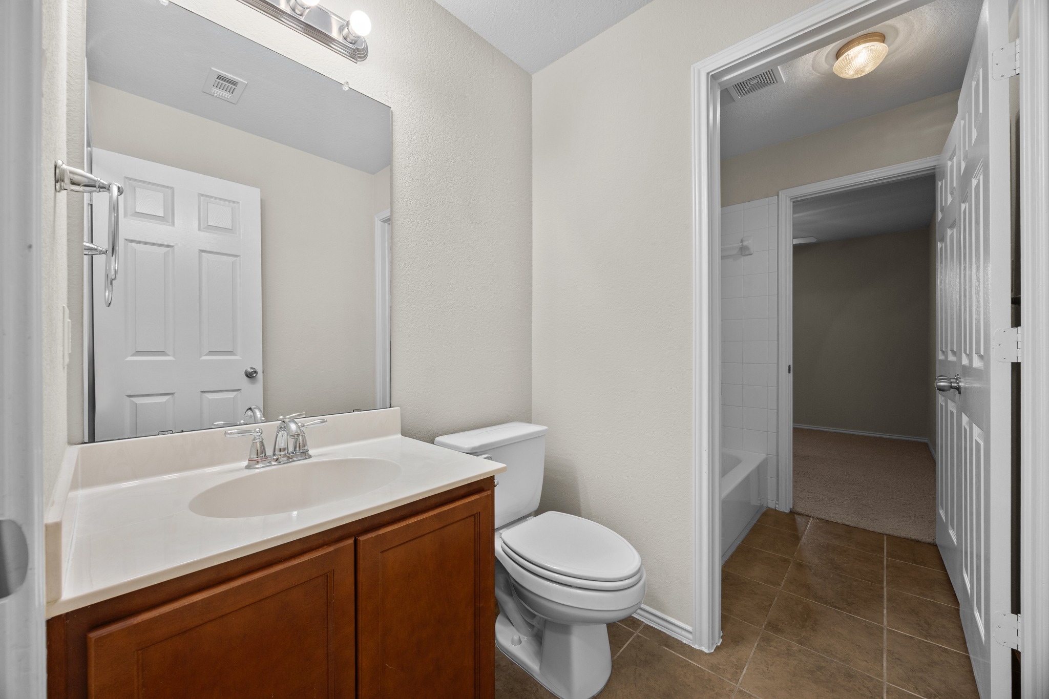 418 Nottingham Loop Kyle, TX 78640 - Photo 25 of 28 Full bathroom featuring a wood-finish vanity with a white countertop, an integrated sink, and a chrome faucet