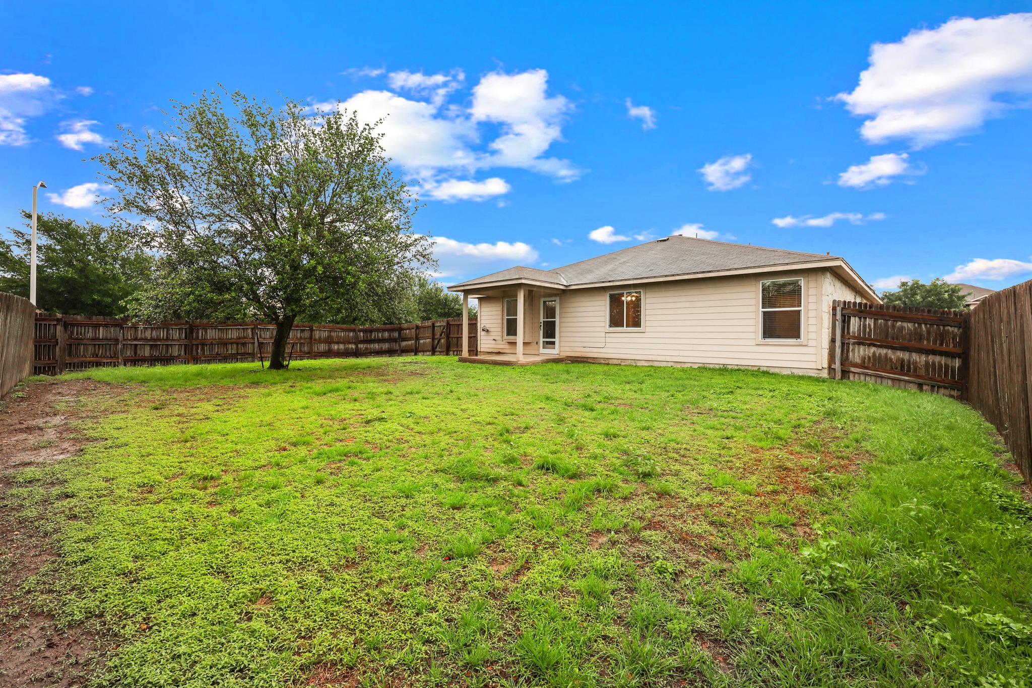 418 Nottingham Loop Kyle, TX 78640 - Photo 27 of 28 Expansive rear yard featuring a mature tree, privacy fencing, and a covered patio