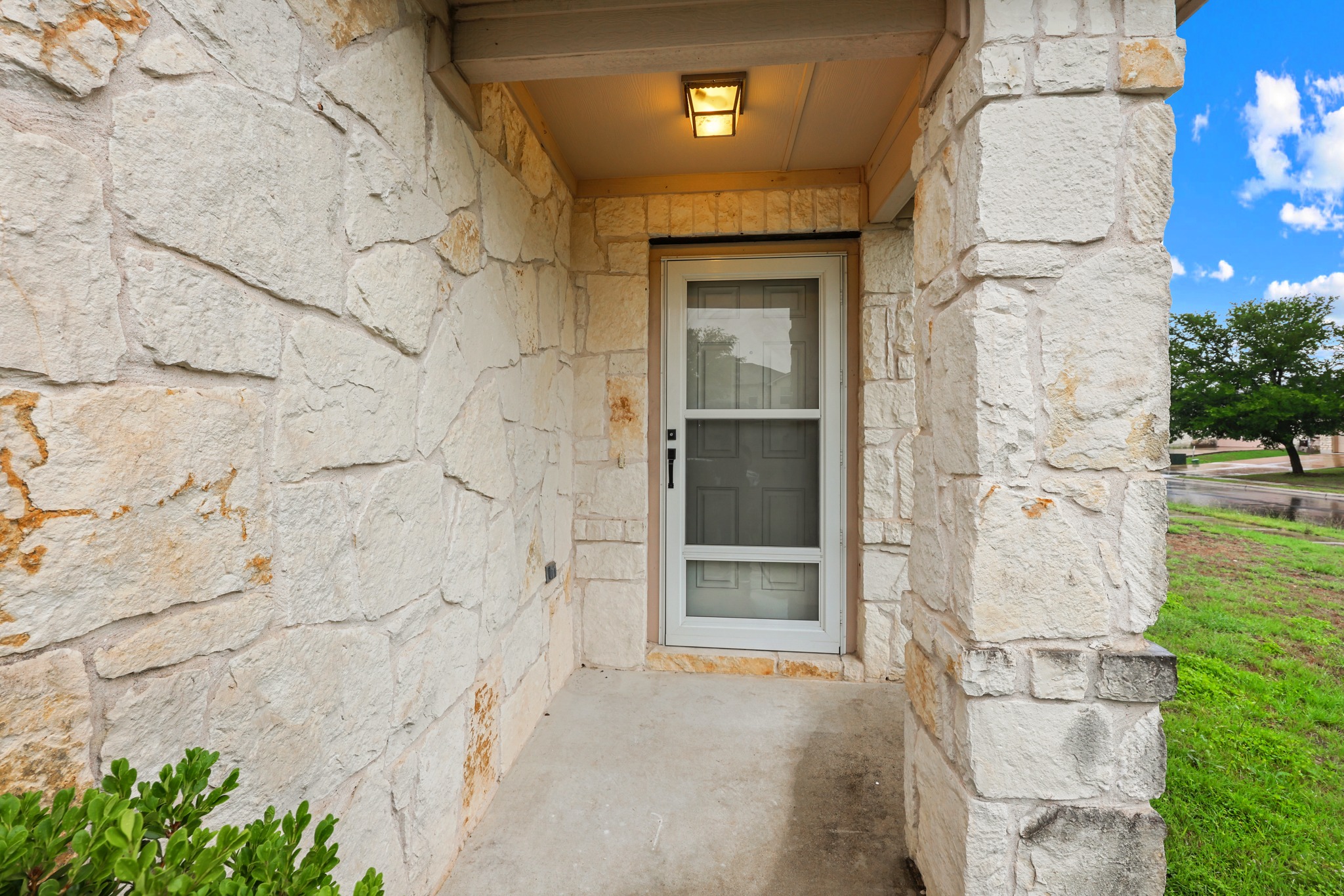 418 Nottingham Loop Kyle, TX 78640 - Photo 4 of 28 Stone façade entry featuring a covered porch, a white screen door, exterior wall sconce, and concrete flooring