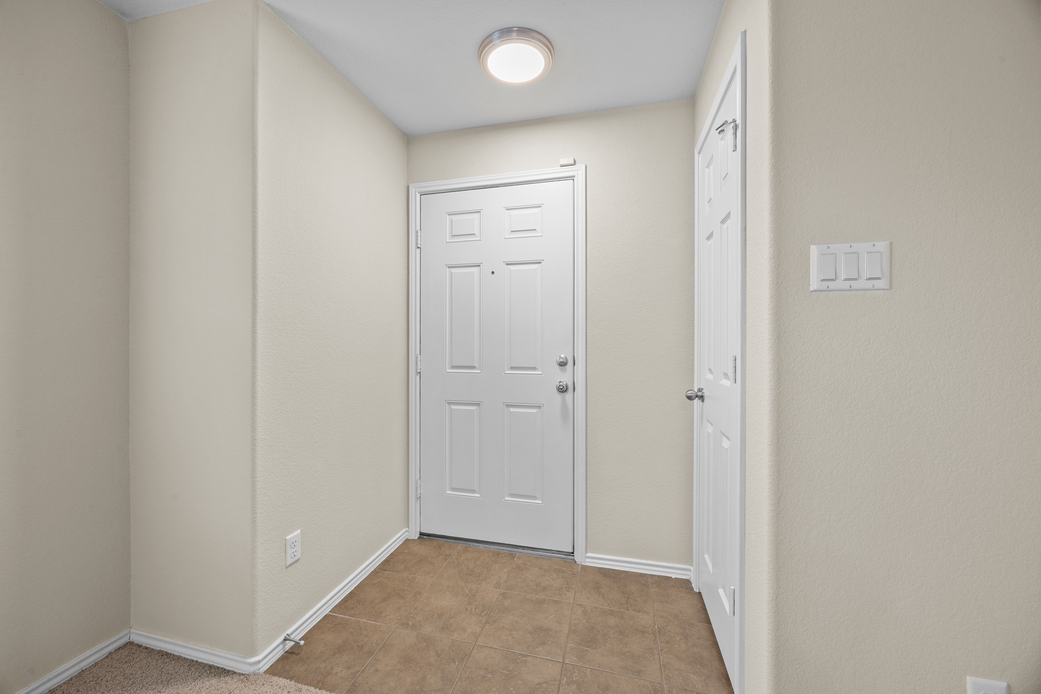 418 Nottingham Loop Kyle, TX 78640 - Photo 5 of 28 Entryway featuring a panel door, ceiling-mounted light fixture, light-colored walls, and tile flooring