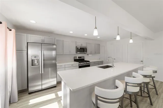 a kitchen with stainless steel appliances a stove a sink a center island and a window