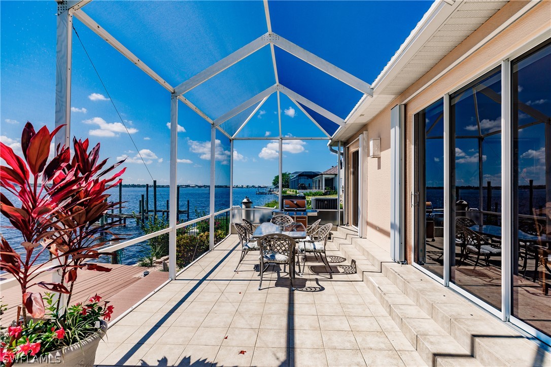5727 Riverside Drive Cape Coral, FL 33904 - Photo 25 of 35 a view of a patio with table and chairs potted plants with wooden floor and fence