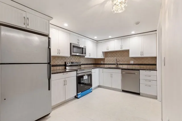 a kitchen with granite countertop a refrigerator stove top oven and sink