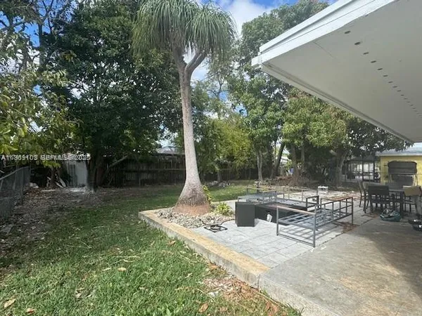 a view of a patio with table and chairs potted plants and large tree