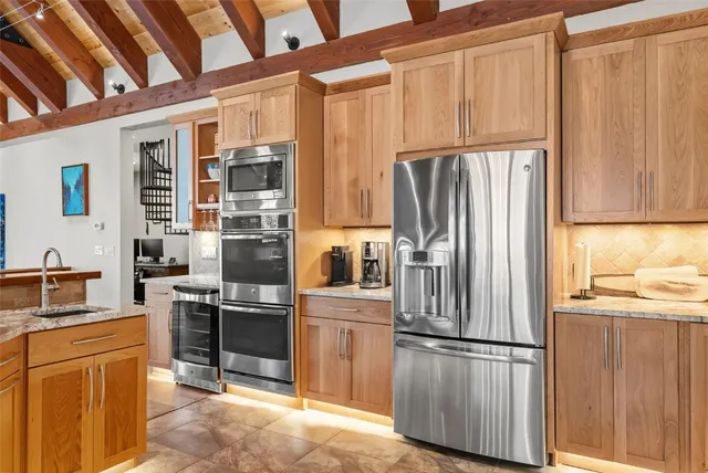 a kitchen with stainless steel appliances granite countertop a refrigerator and a stove top oven