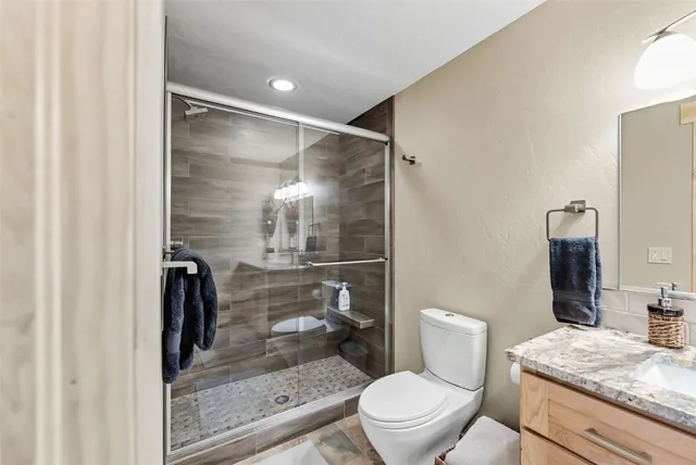 a bathroom with a granite countertop toilet a sink and shower