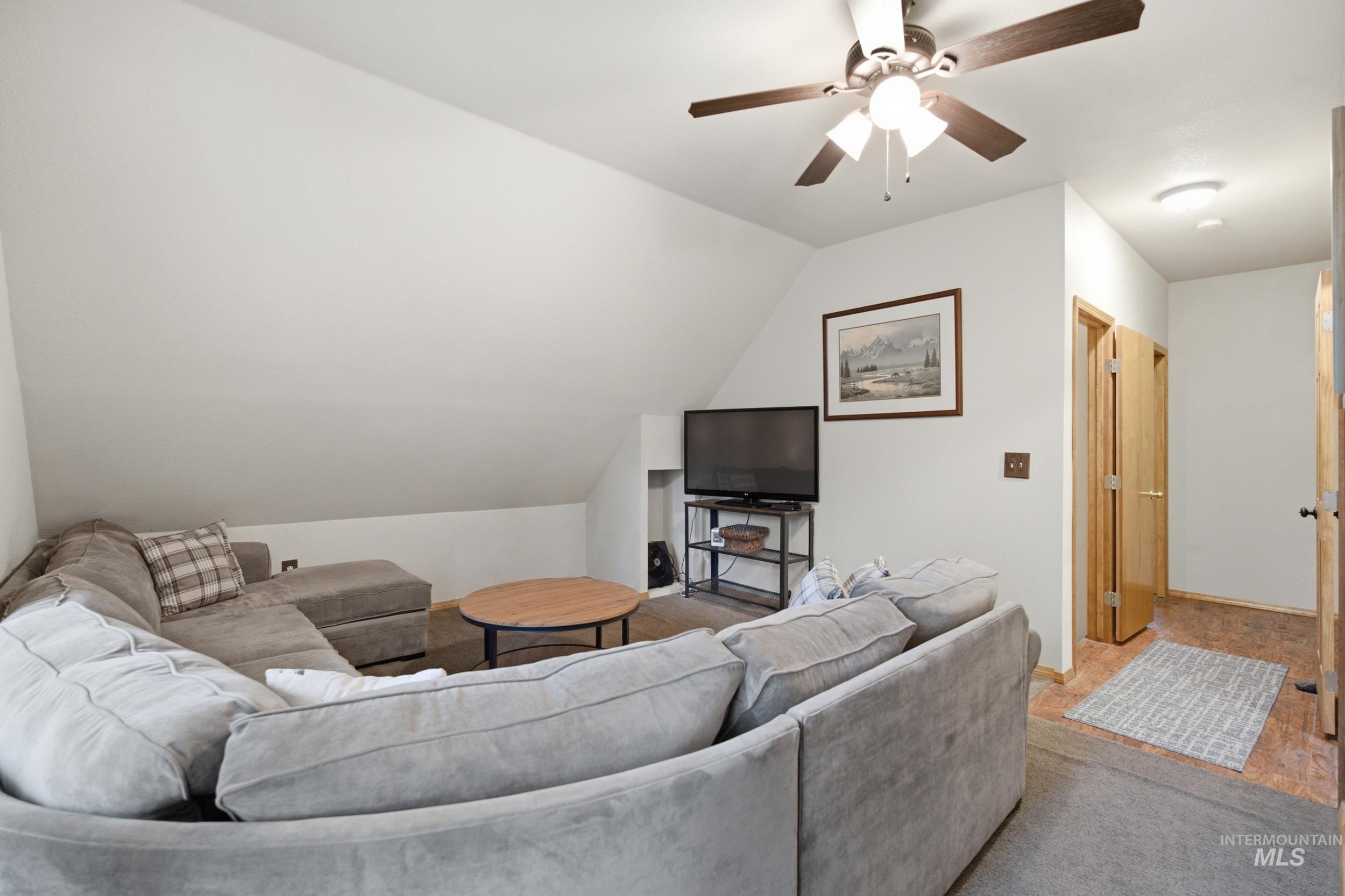 3980 North Pine-Featherville Road Mountain Home, ID 83647 - Photo 32 of 35 Living area featuring a sloped ceiling, ceiling fan, and wood-finish flooring