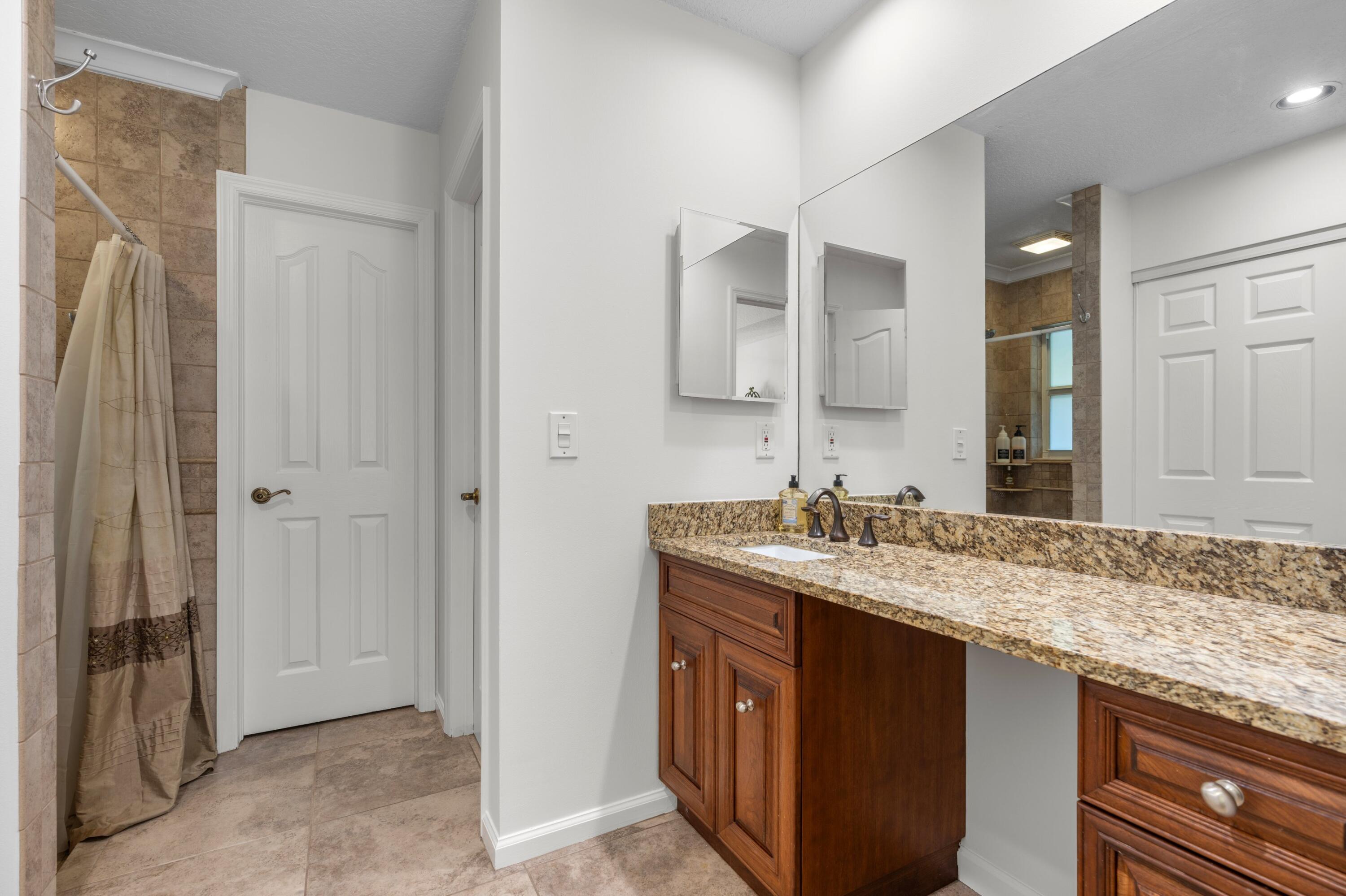 17392 Mellen Lane Jupiter, FL 33478 - Photo 14 of 38 a bathroom with a granite countertop sink and a mirror