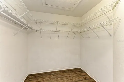 an empty room with wooden floor ceiling fan and windows
