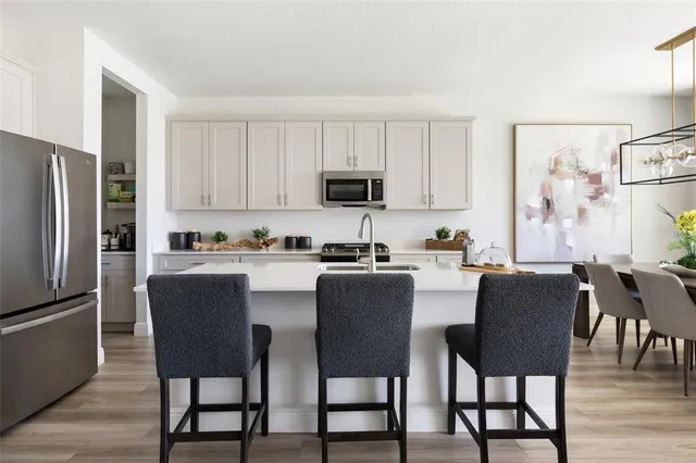 a kitchen with stainless steel appliances granite countertop a dining table chairs refrigerator and cabinets