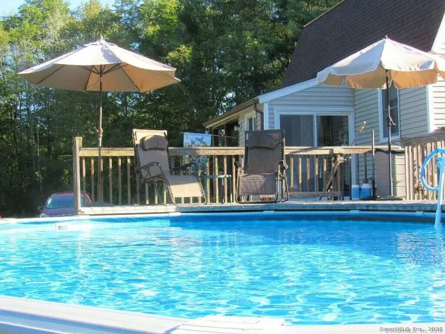 a view of pool with lawn chairs under an umbrella