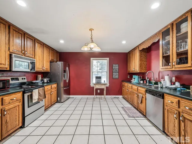 a large kitchen with stainless steel appliances granite countertop a stove top oven a sink dishwasher a dining table and chairs with wooden floor