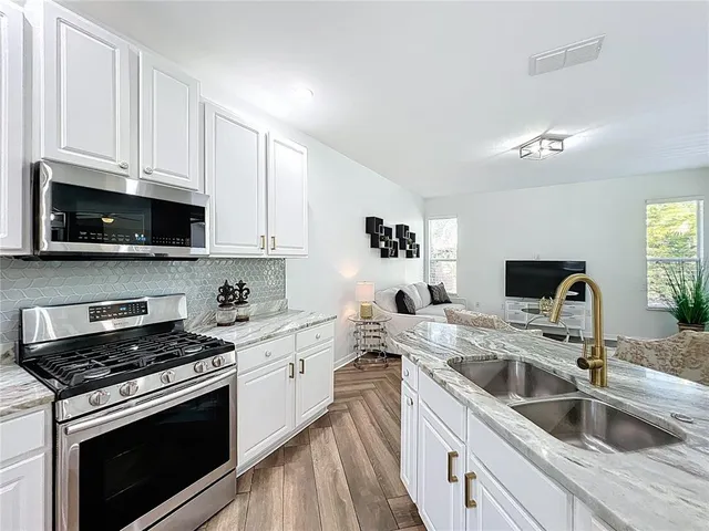 a kitchen with granite countertop a sink a stove and cabinets