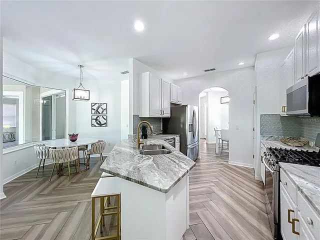 a kitchen with granite countertop kitchen island stainless steel appliances a stove a sink a microwave a refrigerator and cabinets