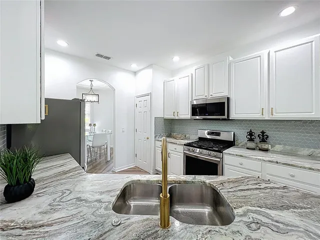 a kitchen with granite countertop a sink stove and refrigerator
