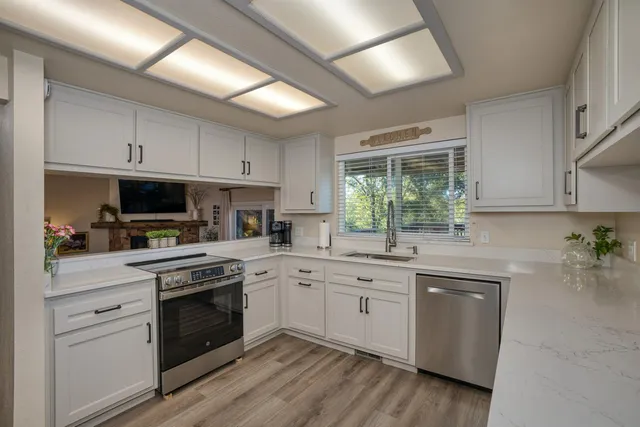 a kitchen with a stove a sink and dishwasher with wooden floors