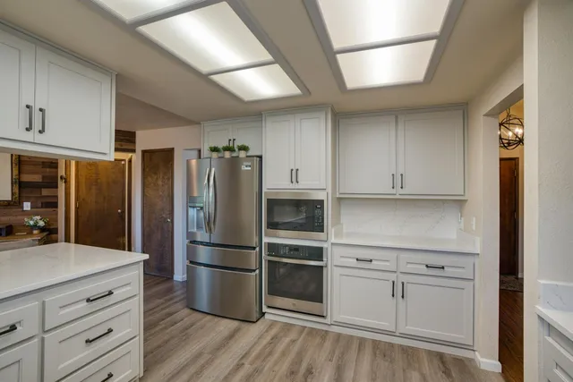 a kitchen with a refrigerator stainless steel appliances wooden floor and cabinets