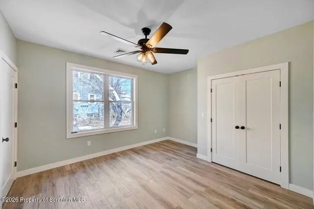 a view of an empty room with window and wooden floor