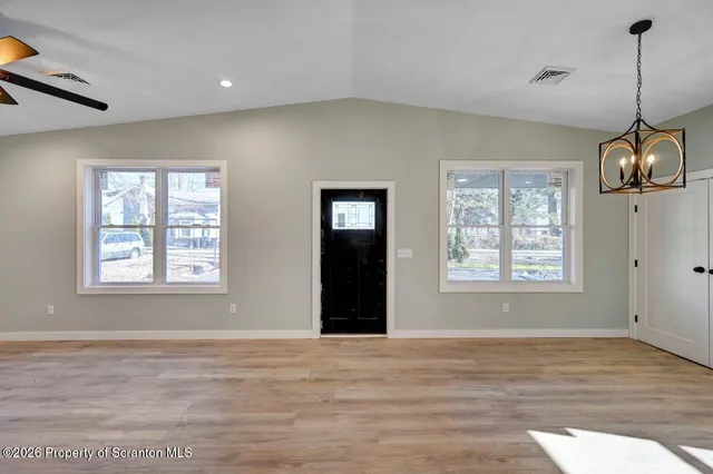 a view of an empty room with window and hardwood floor