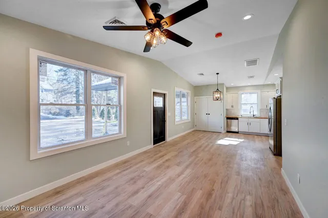 a view of an empty room with a window and wooden floor