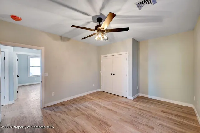 a view of a room with wooden floor and a ceiling fan