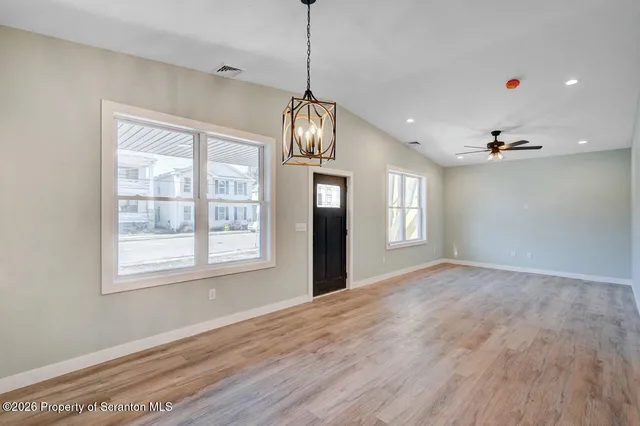 a view of an empty room with window and wooden floor