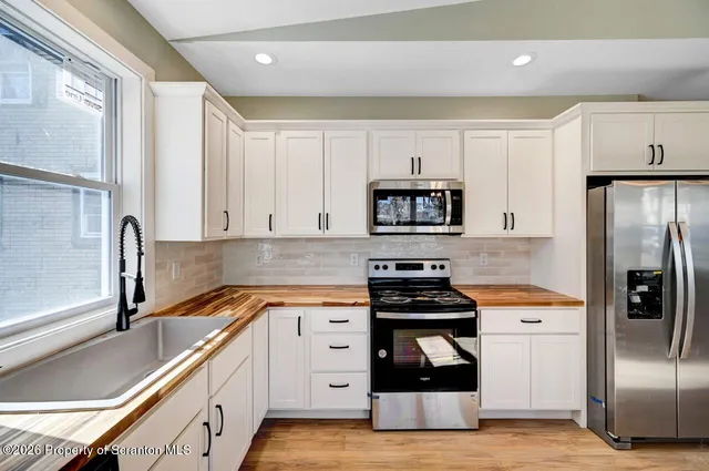 a kitchen with white cabinets and stainless steel appliances