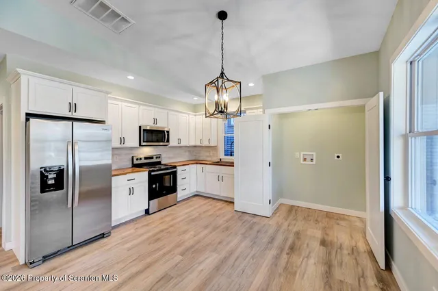 a kitchen with stainless steel appliances granite countertop a refrigerator a oven a sink dishwasher and a flat screen tv