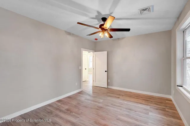 a view of a room with wooden floor and ceiling fan