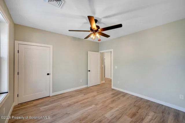 a view of a room with wooden floor and a ceiling fan