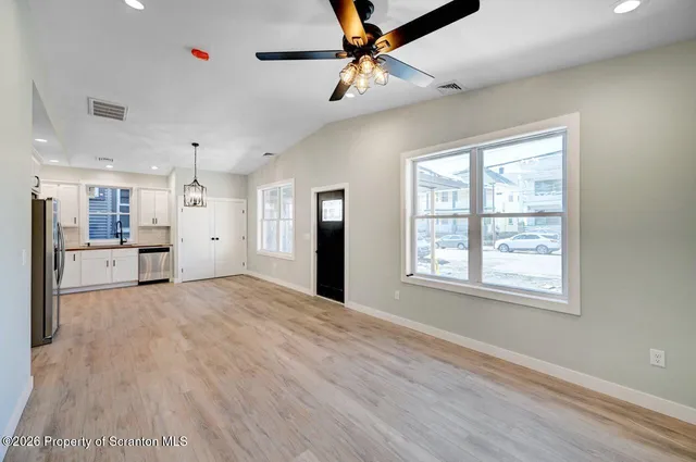 a view of an empty room with a window and kitchen view