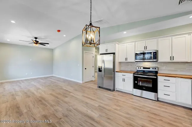 a view of a kitchen with stainless steel appliances granite countertop a refrigerator and a stove top oven