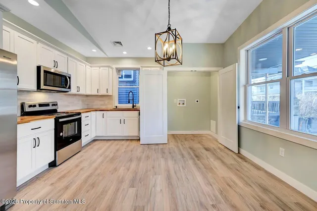 a kitchen with granite countertop a stove top oven a sink dishwasher a refrigerator and a dining table with wooden floor