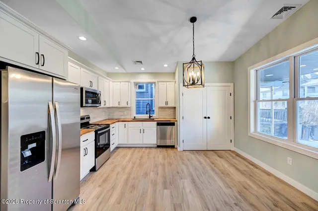 a kitchen with stainless steel appliances granite countertop a refrigerator a stove top oven a sink dishwasher and wooden floor