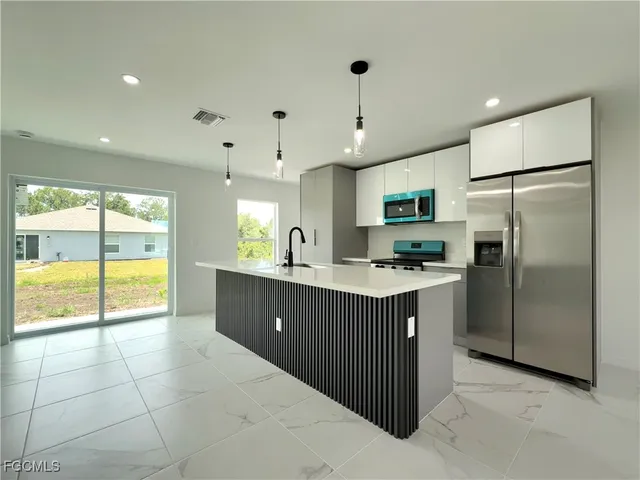 a kitchen with kitchen island a refrigerator a sink a stove and a cabinets