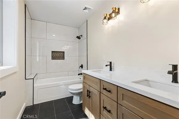 a bathroom with a granite countertop sink a toilet and bathtub