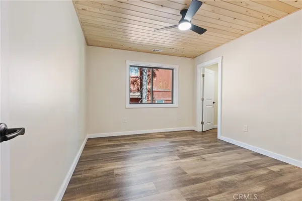 an empty room with wooden floor ceiling fan and windows