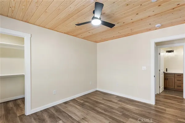 an empty room with wooden floor cabinet and windows