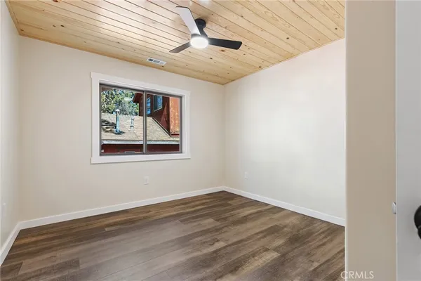 an empty room with wooden floor and window