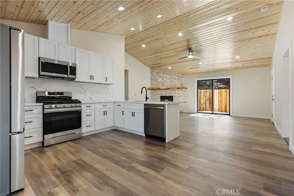 a large kitchen with stainless steel appliances granite countertop a stove top oven a sink dishwasher and a refrigerator with wooden floor