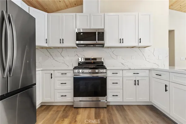 a kitchen with stainless steel appliances granite countertop a refrigerator stove and white cabinets