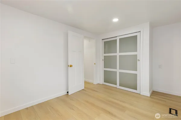 a view of an empty room with wooden floor and closet