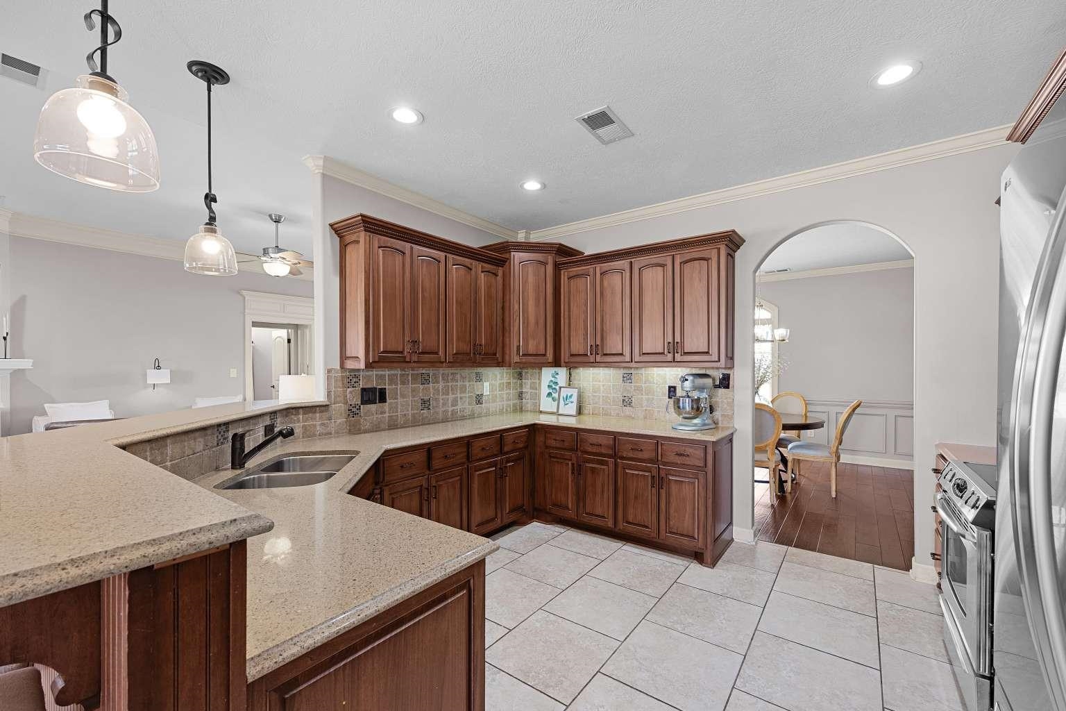 621 Wortham Cemetery Road Bells, TN 38006 - Photo 11 of 25 Kitchen with backsplash, arched walkways, crown molding, light tile patterned floors, and pendant lighting
