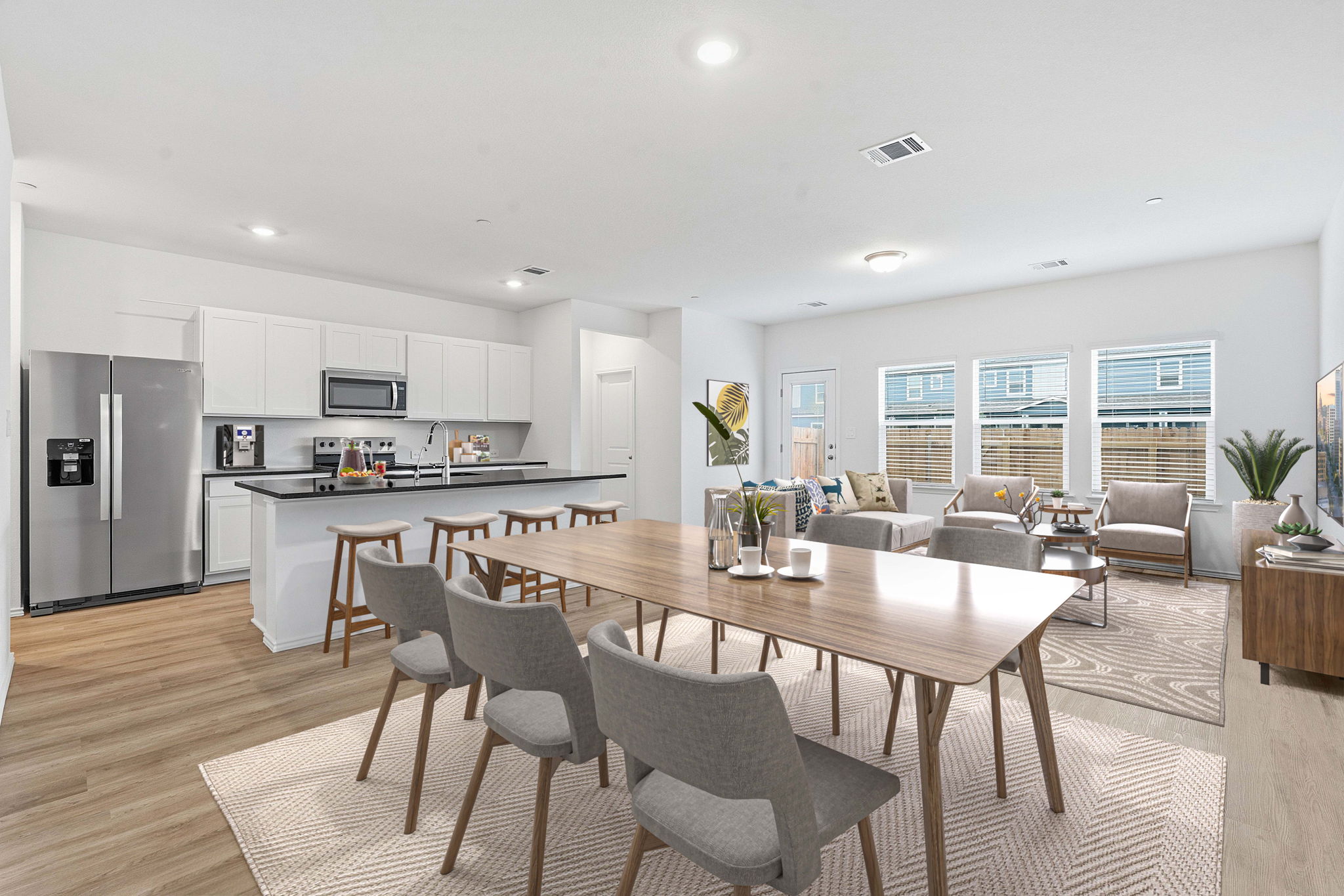 164 Cinnabar Lane, Unit 2 Kyle, TX 78640 - Photo 3 of 21 Open-concept living area featuring wood-finish flooring, a kitchen with white cabinetry and black countertops, stainless steel appliances, and multiple windows providing natural illumination