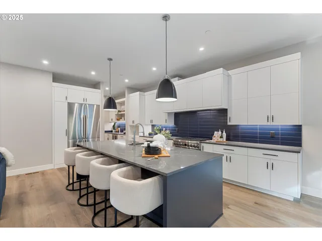 a kitchen with stainless steel appliances kitchen island granite countertop a sink a stove a dining table and chairs