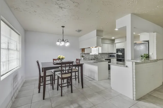 a kitchen with a dining table chairs and refrigerator